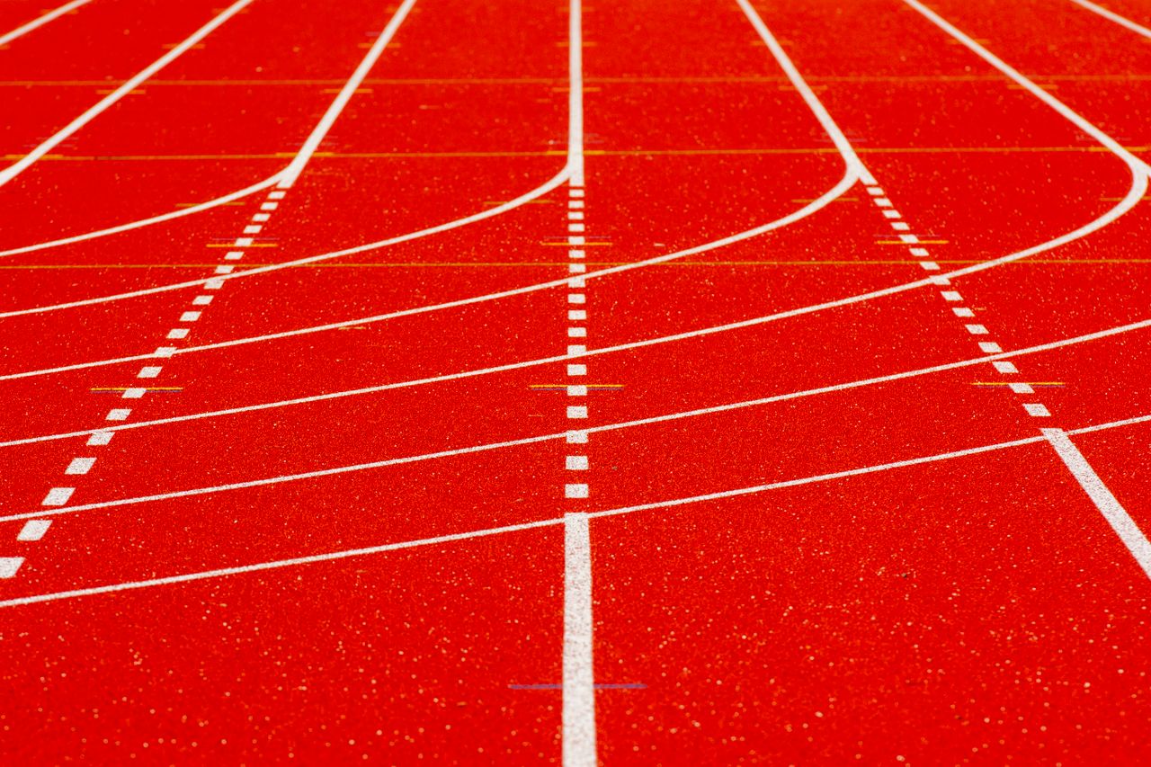 Close-up view of a bright red running track with white lines in a sports venue.